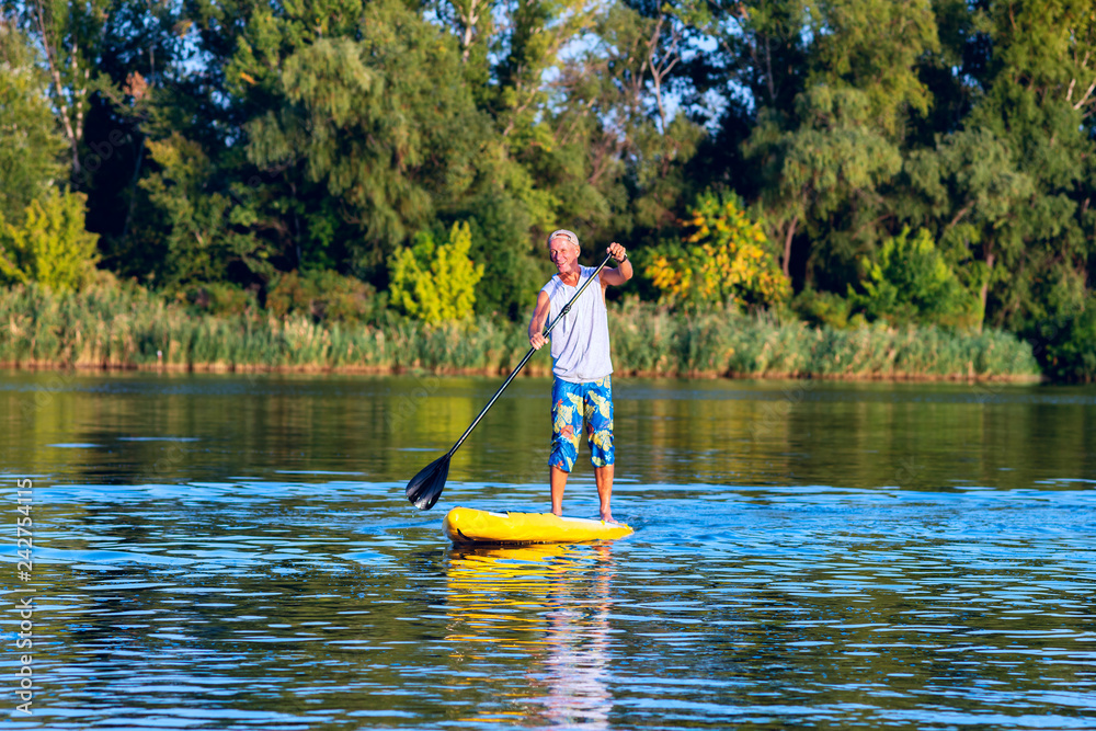 Happy man is training on a SUP board