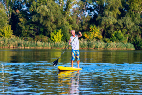 Obraz na płótnie Happy man is training on a SUP board w salonie