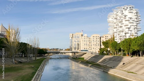 Montpellier is a city in southern France and the Lez is a coastal river. It is the main river crossing Montpellier. Filmed in december. Blue sky. Modern buildings next to the river banks.  photo