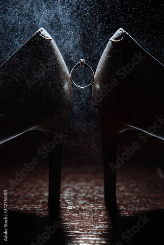Ring and shoes. Very unusual and beautiful photo of the ring between the shoes on the dark background
