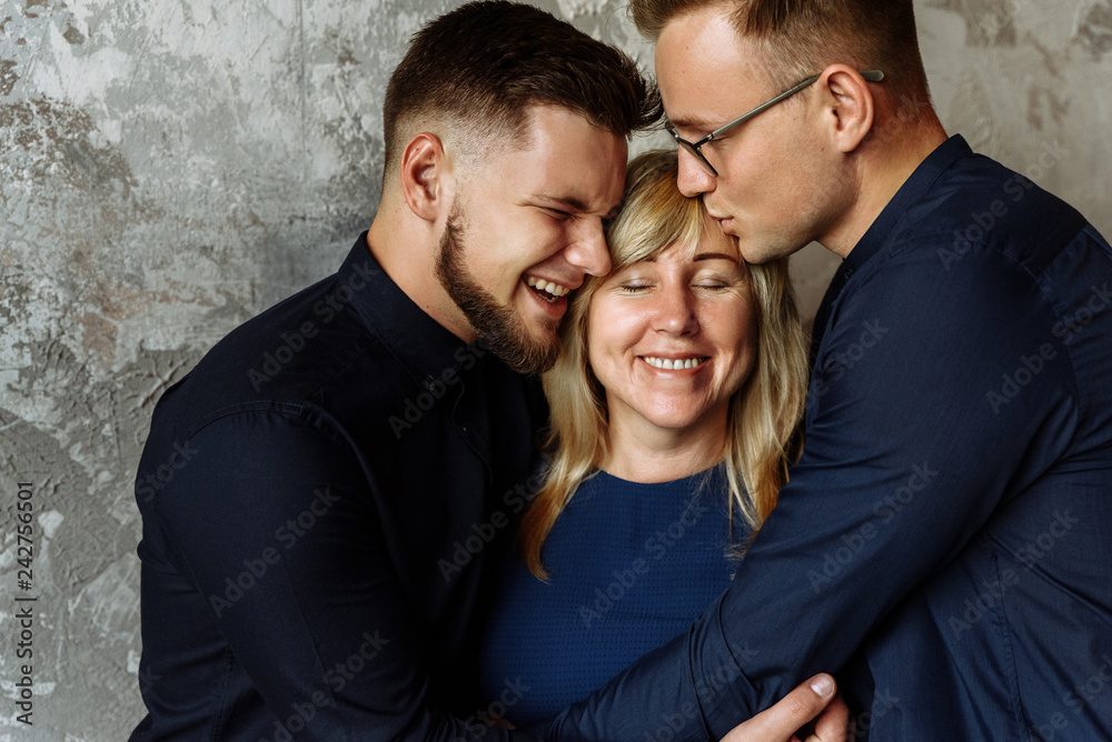 Mother and her adult sons. Happiness. Two adult sons kiss and hugs their beloved mother. Mother's happiness