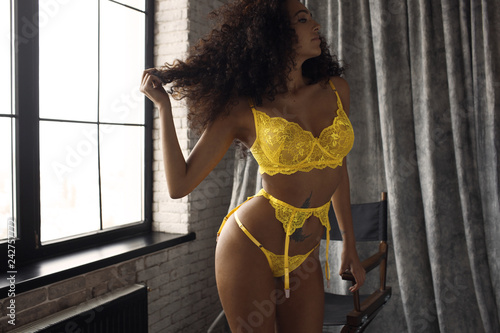 curly girl in yellow lace underwear at the window