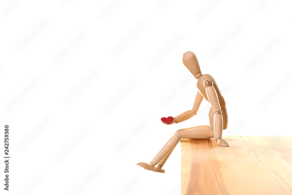 Wooden puppet with small heart sitting on table against white background. Relationship problems Wooden puppet with small heart sitting on table against white background. Relationship problems