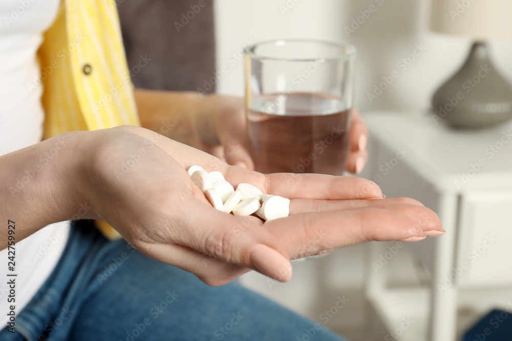 Woman with pills and glass of water indoors, closeup Woman with pills and glass of water indoors, closeup