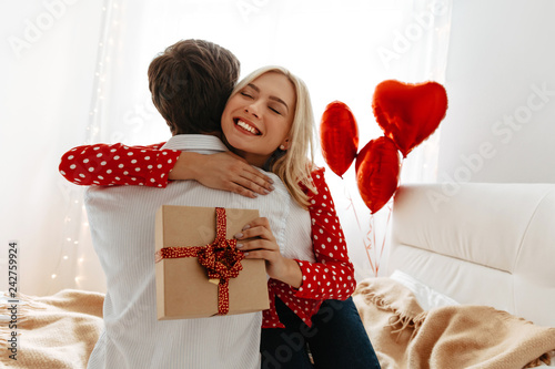Couple. Love. Valentine's day. Man and woman are hugging, she is holding a gift box and smiling