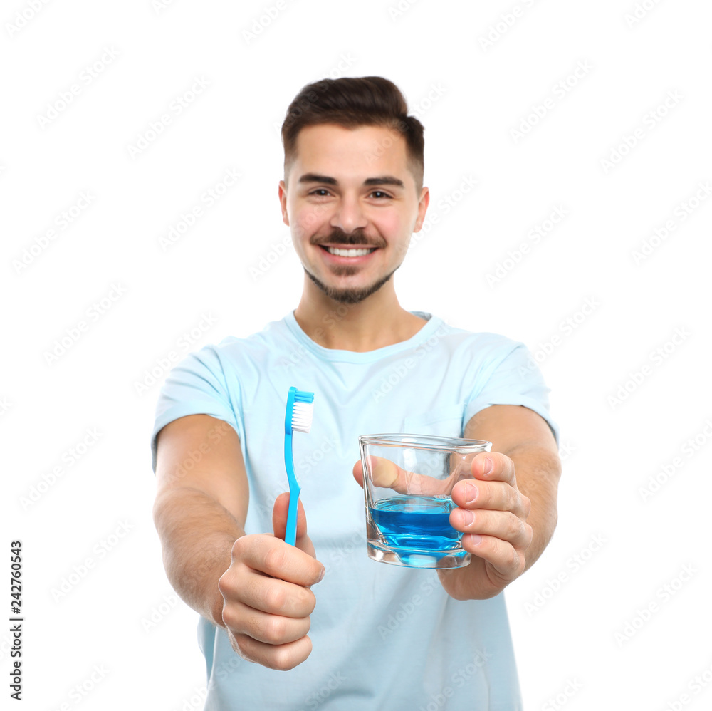 Young man holding toothbrush and glass with mouthwash on white background. Teeth care Young man holding toothbrush and glass with mouthwash on white background. Teeth care