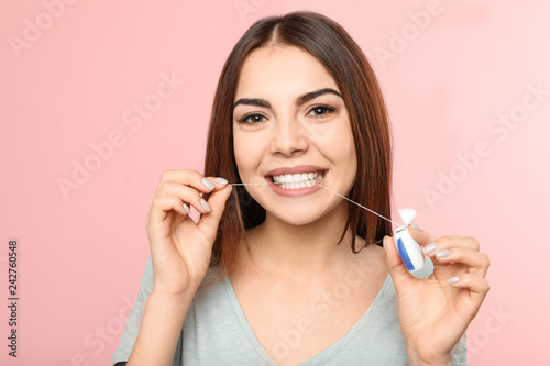 Fototapeta Naklejka Na Ścianę i Meble -  Young woman flossing teeth on color background