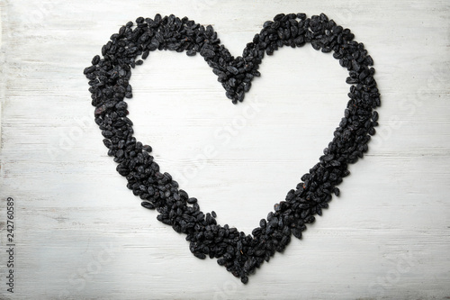 Frame made of raisins on wooden background, top view with space for text. Dried fruit as healthy snack