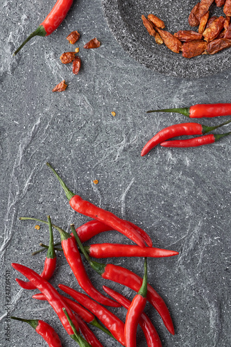 Close-up on red hot chili peppers, fresh and dry, on grey stone, flat lay