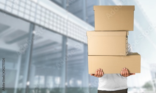 Delivery man carrying stacked boxes in front of face against