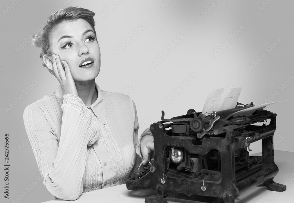 Naklejka premium Young blonde female writer using typing machine, black and white