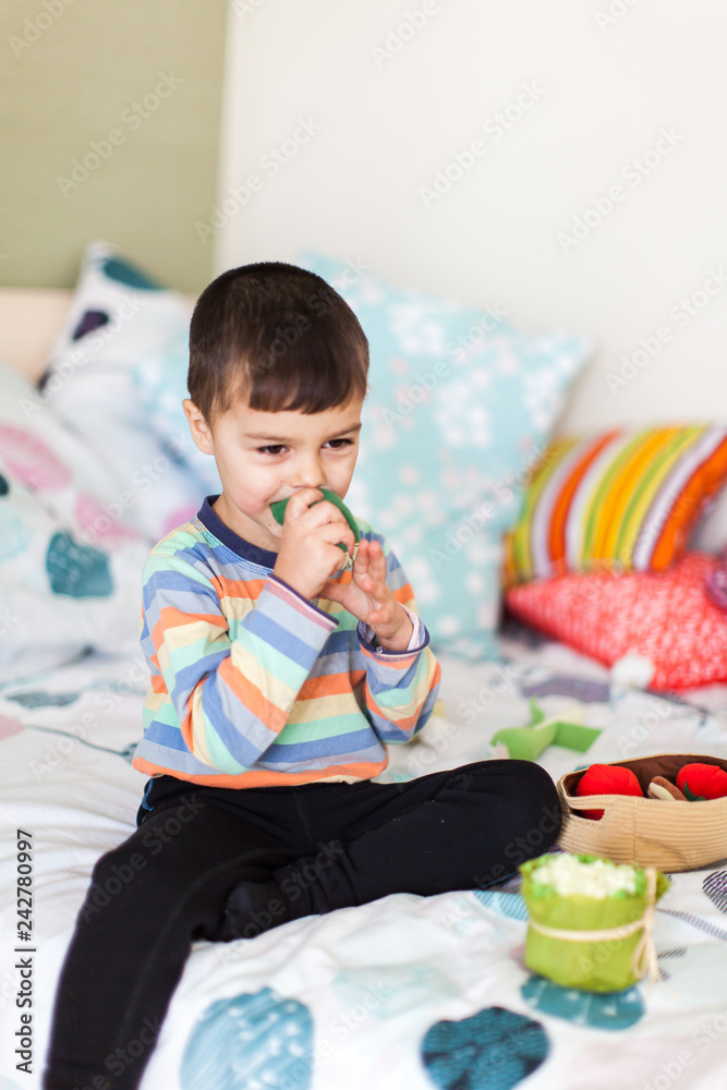 cute little boy is playing with colorful soft vegetables sitting on bed. cute little boy is playing with colorful soft vegetables sitting on bed.