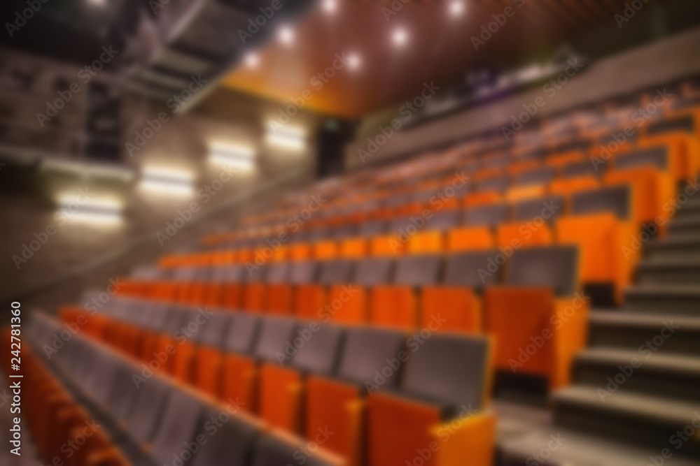 Blurred image of empty theatre or cinema auditorium hall with rows of seats or chairs, defocused