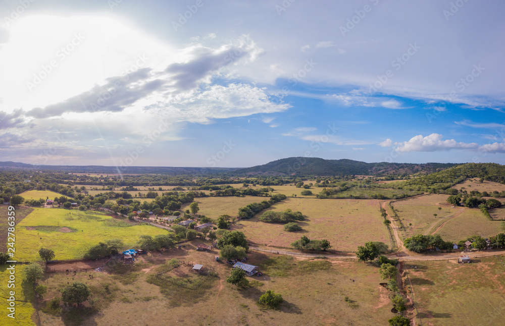 Naklejka premium Vista Aérea de Campo con Casas y Montañas
