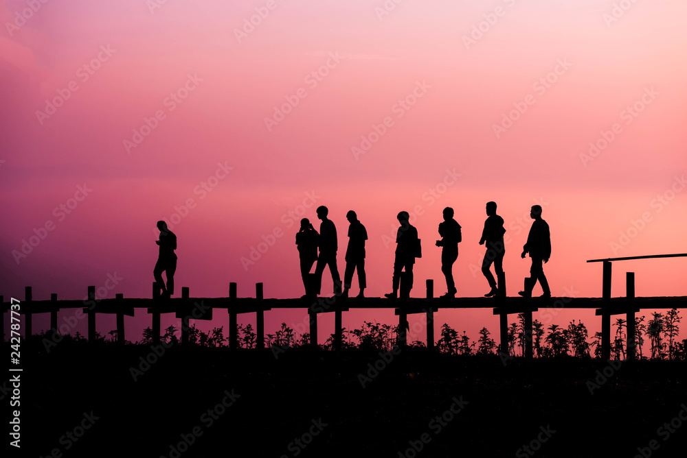 Walking people Silhouette team friends group of people walking on the wooden bridge on hill with sunrise or sunset
