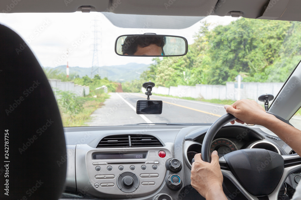 Hand male holding the steering wheel to drive the car on asphalt road Hand male holding the steering wheel to drive the car on asphalt road