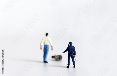 The concept of domestic violence. A miniature man is standing with a miniature woman and a miniature police.
