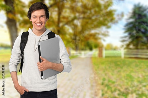 Male student with laptop on background