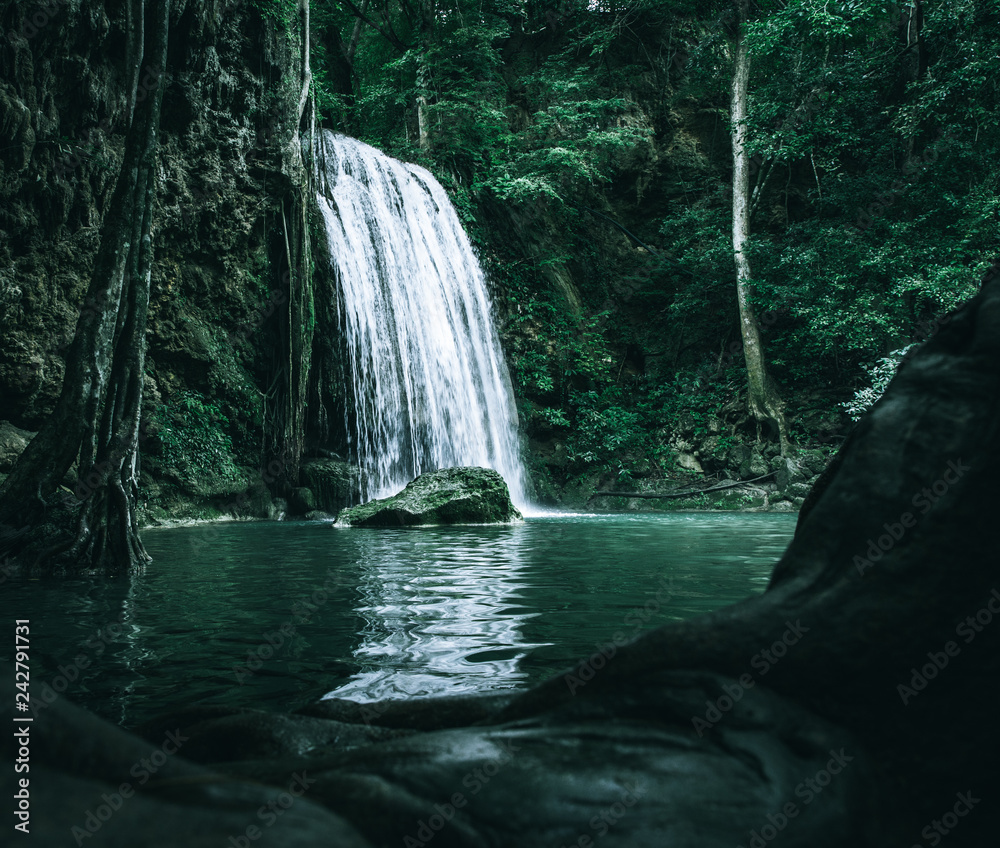 Naklejka premium view of a beautiful waterfall in Thailand in a green jungle and clean environment in a moody green tone look surrounded with big trees and clear fresh green water which suggests an eco environment