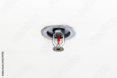 Fire sprinkler with vakuum sealed glass tube installed in the ceiling office building. Fire protection system equipment isolated in white background.