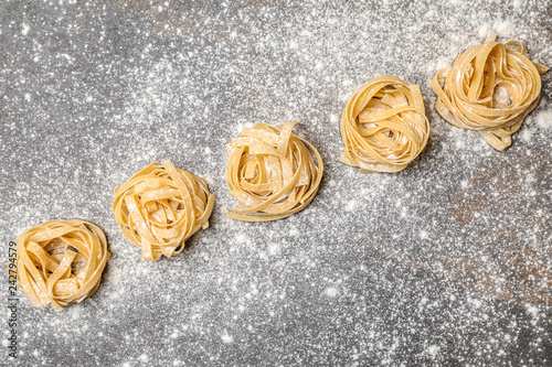 Uncooked noodles with flour on grey background