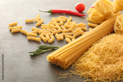 Assortment of uncooked pasta on grey table