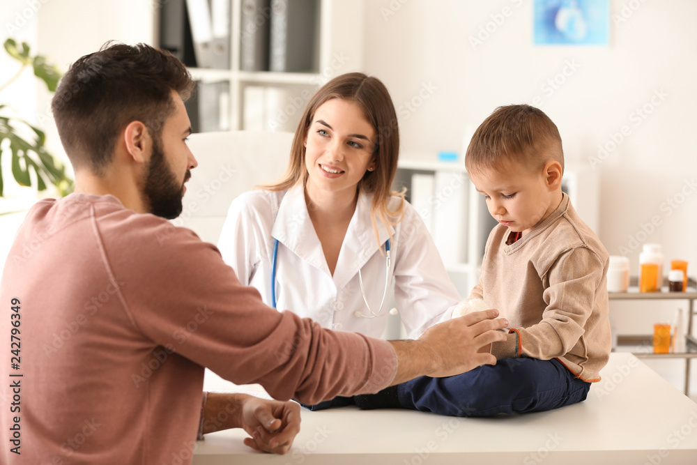 Fototapeta premium Young father with his little son visiting doctor in clinic