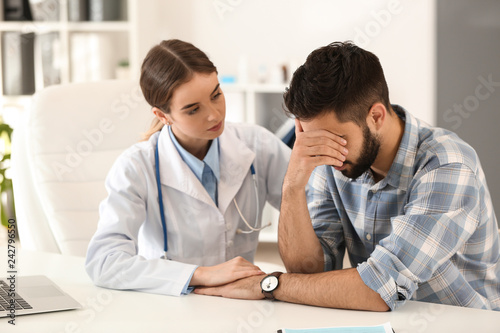 Female doctor calming male patient in clinic