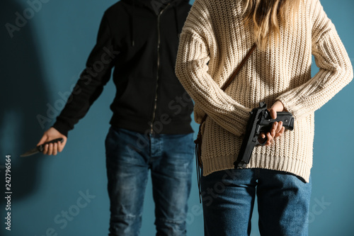 Young woman is going to defend herself from attack by male bandit on color background photo