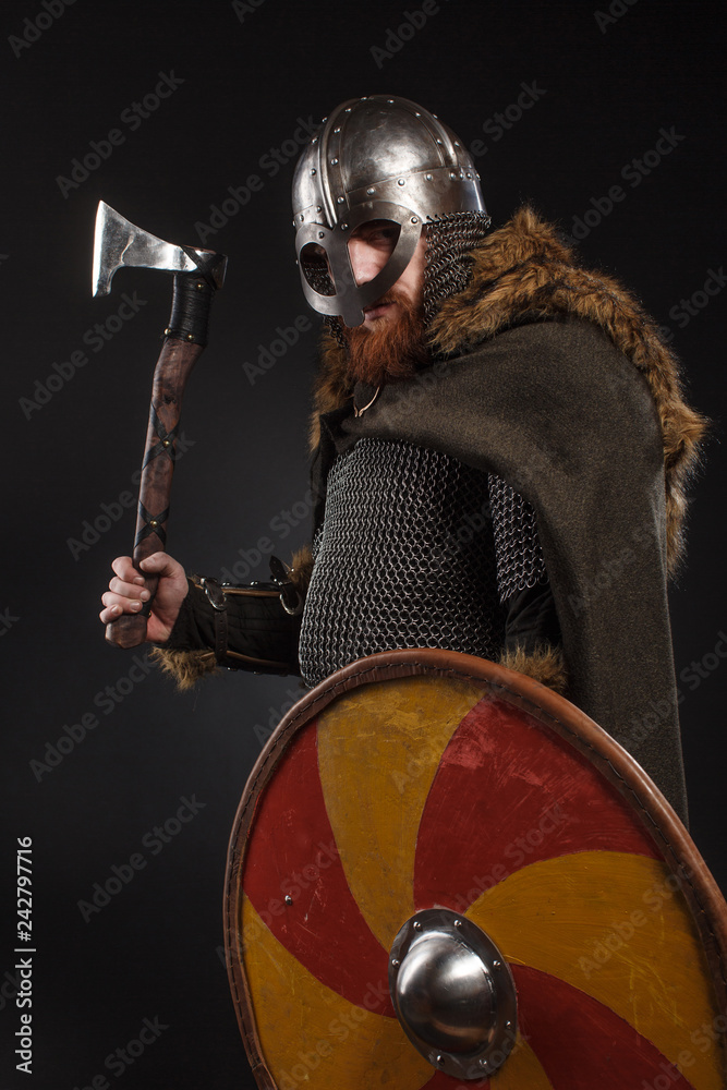 Naklejka premium Warrior Viking in full arms with axe and shield on dark background