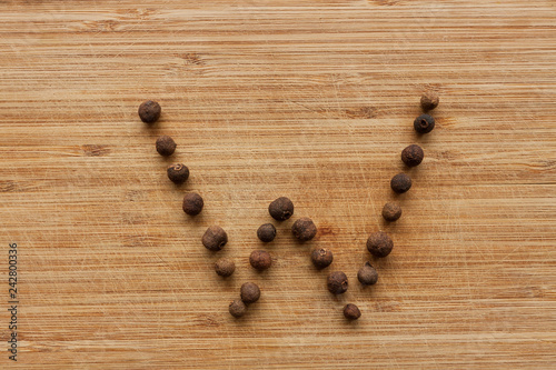 Capital characters made of peppercorns. Alphabet letters on wood background.