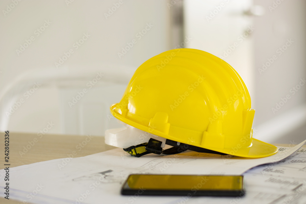 Selective focus of helmet Construction plans ,pem and blueprints on wooden table with sunshine background. Selective focus of helmet Construction plans ,pem and blueprints on wooden table with sunshine background.