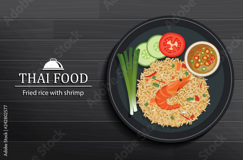 Thai food in the dish on black wooden table top view. Fried rice with shrimp.