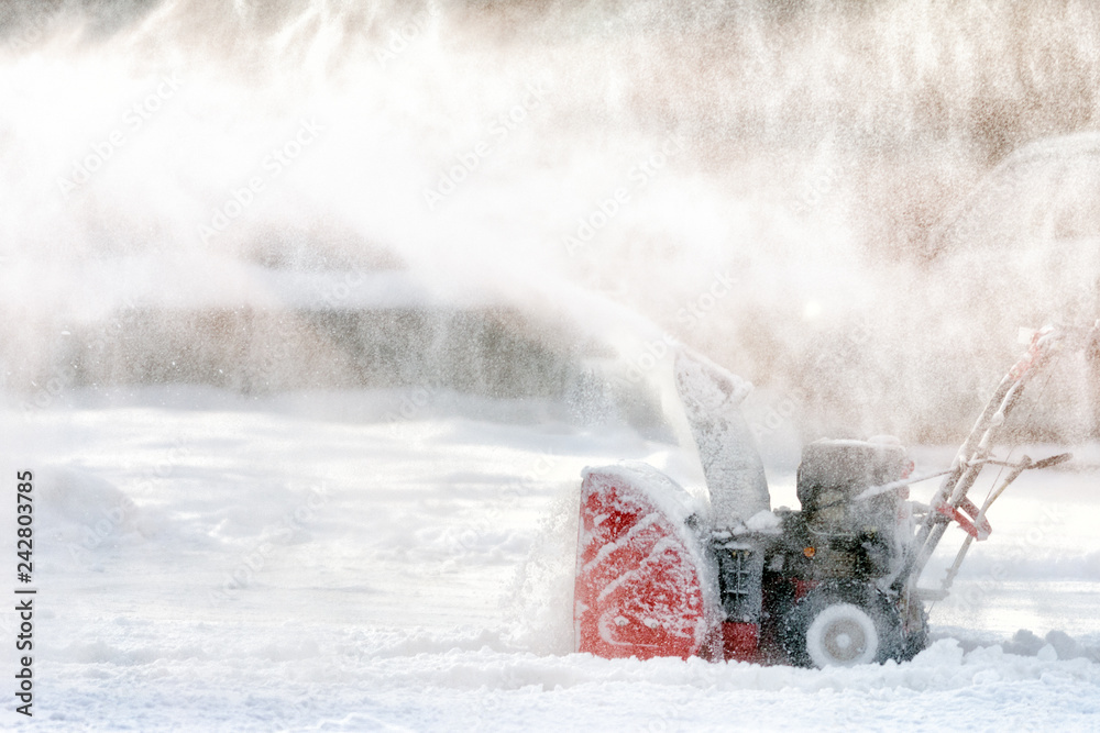 worker cleaning white snow by using snow blower on sunny winter wonderland day against sun background worker cleaning white snow by using snow blower on sunny winter wonderland day against sun background