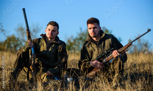 Hunting with friends hobby leisure. Hunters gamekeepers relaxing. Rest for real men concept. Discussing catch. Hunters with rifles relaxing in nature environment. Hunter friend enjoy leisure in field