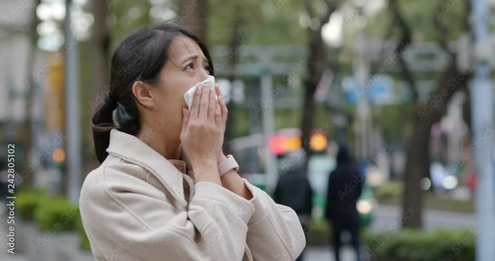 Woman sneeze at outdoor city in the winter time Woman sneeze at outdoor city in the winter time