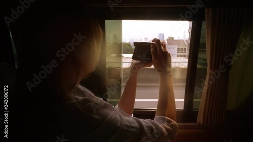 A woman takes photos of skyscrapers from a modern car.