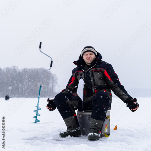 Ice fishing. Disappointed fisherman after unsuccessful winter fishing on the lake at winter day
