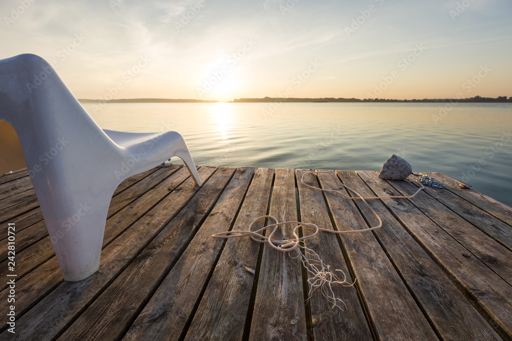 Obraz premium Landscape with empty chair in wooden footbridge on Powidzkie Lake in Poland.