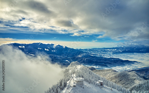 Aerial view over the spectacular ski slopes in the Carpathians mountains, Panoramic view over the ski slope Poiana Brasov ski resort in Transylvania,Romania,Europe,Pine forest covered in snow  photo