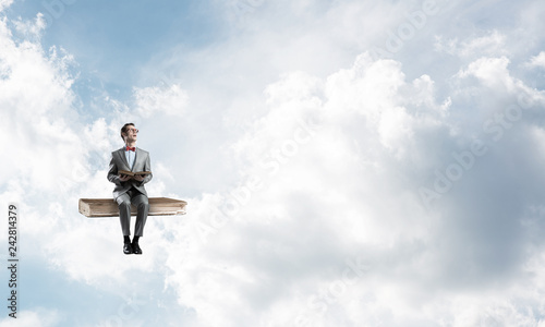 Young businessman or student floating in blue sky and studying the science