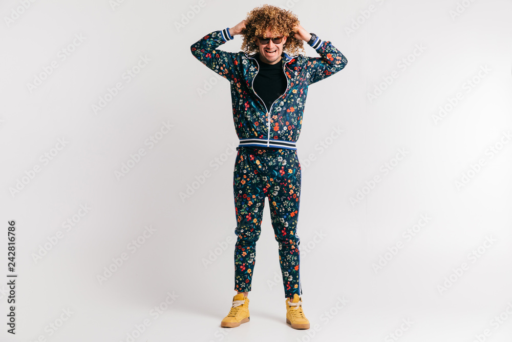 Fototapeta premium Adult shylish man in fashion clothes, yellow sneakers posing on white studio background. Excited bizarre crazy shocked male shouting, tearing hair. Surprised funny happy young brazilian guy screaming.