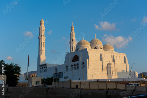 Al Ameen Mosque, Muscat Oman in the late afternoon as the sun sets against the blue sky on the mosque and surrounding mountains.  photo