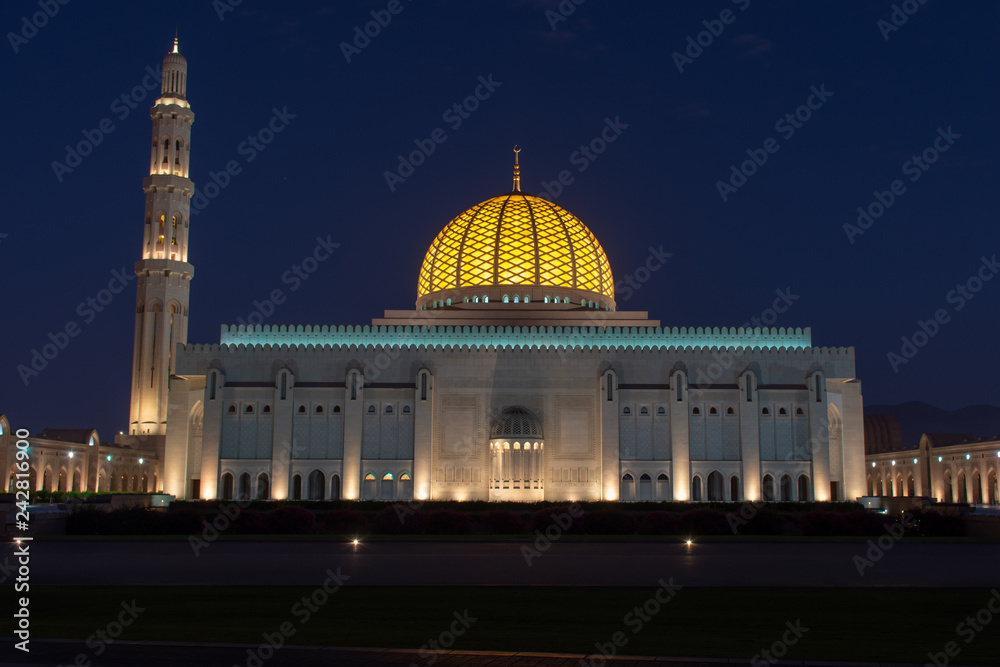 Sultan Qaboos Grand Mosque, Muscat, Oman during the early evening hours in the dark blue sky of sunset showing off the glowing dome.