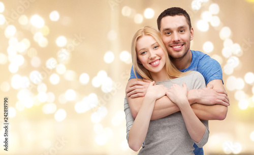 love, relationships and people concept - smiling couple hugging over beige background with festive lights