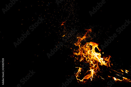 Burning woods with firesparks, flame and smoke. Strange weird odd elemental fiery figures on black background. Coal and ash. Abstract shapes at night. Bonfire outdoor on nature. Strenght of element.