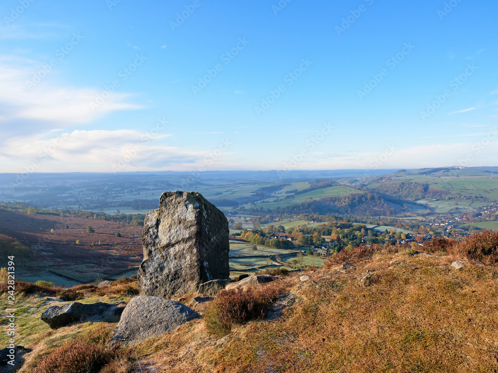 A single upright rectangular piece of gritstone standing on Curbar Edge in the autumn sunlight.