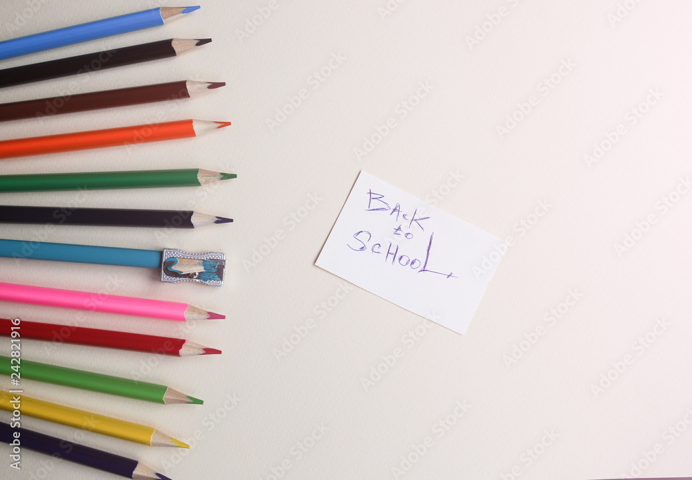 Colour pencils with sharpener lying on pastel beige background. Back to school concept sign written. Colorful art studying and painting process. Drawing with pencils. Colour pencils with sharpener lying on pastel beige background. Back to school concept sign written. Colorful art studying and painting process. Drawing with pencils.