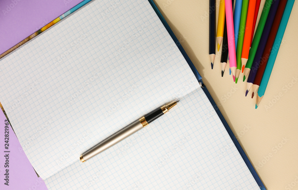 Color pencils lying on pastel purple and beige background near squared notebook. Back to school concept. Colorful art studying and painting process. Copy space place for postcard wish.