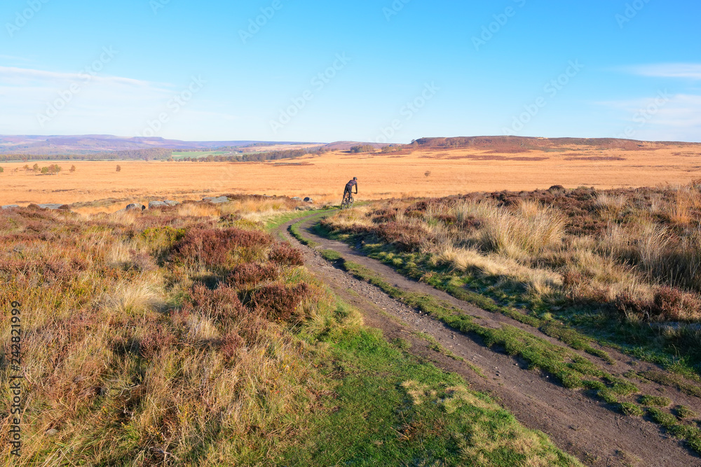 Fototapeta premium Cycling across moorland behind Curbar Edge in the Derbyshire Peak District
